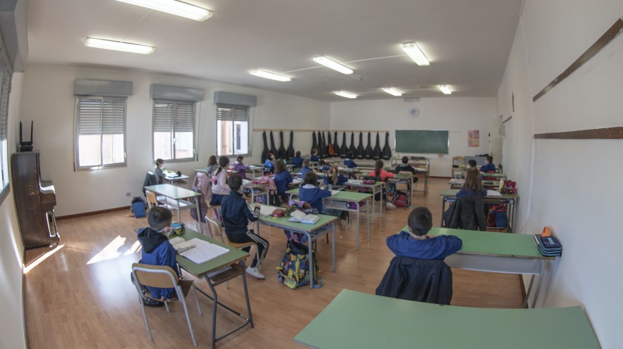 Una aula con gli alunni di spalle che ascoltano l'insegnante